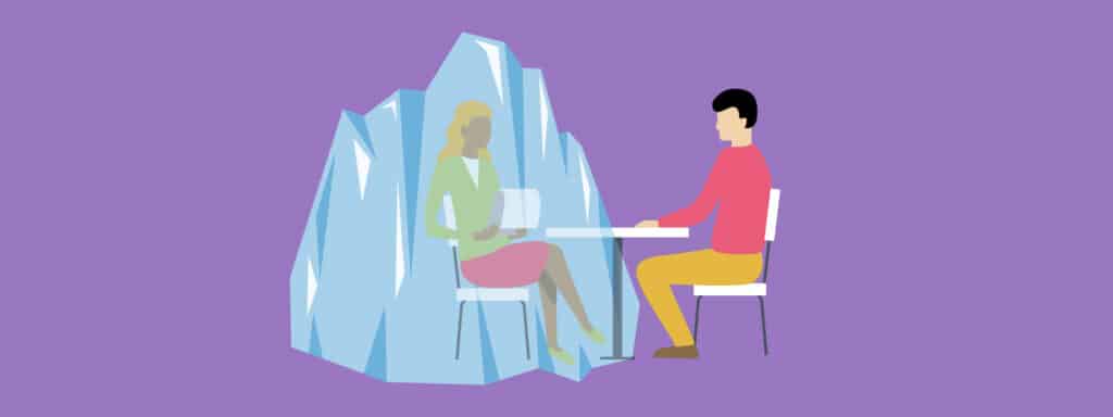 An illustration of a man and a woman sitting at a table. The woman is surrounded by large blue ice crystals, while the man sits across from her on a plain chair. The background is purple.