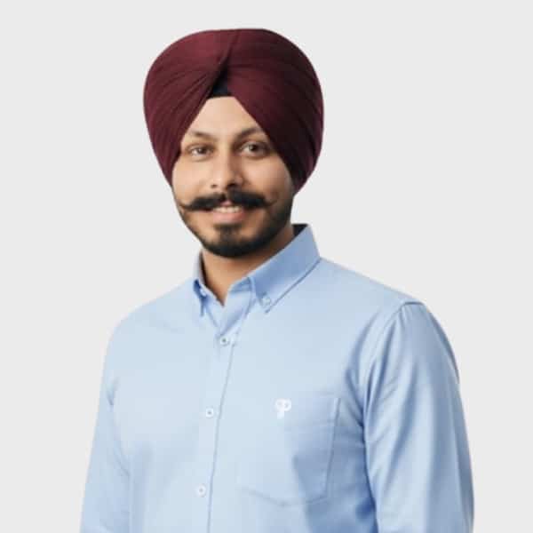 A man with a neatly groomed mustache and beard, wearing a maroon turban and a light blue collared shirt, smiles at the camera against a plain background—reflecting the professionalism valued by an IT staffing agency in Toronto.