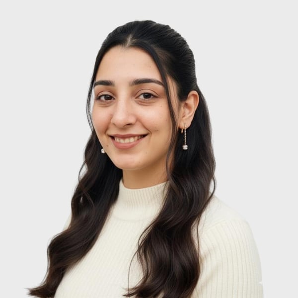 A young woman with long dark hair, wearing a white ribbed turtleneck sweater and drop earrings, smiles at the camera against a plain light background—perfect for representing an IT staffing agency in Toronto.