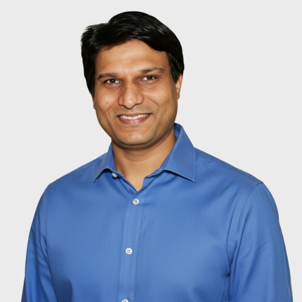 A man with short dark hair, wearing a blue button-up shirt, smiles at the camera against a plain light background, representing an IT staffing agency in Toronto.