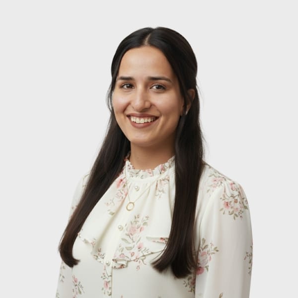 A woman with long dark hair, wearing a white floral blouse and a necklace, smiles at the camera against a plain light background, reflecting the approachable professionalism of an IT staffing agency in Toronto.