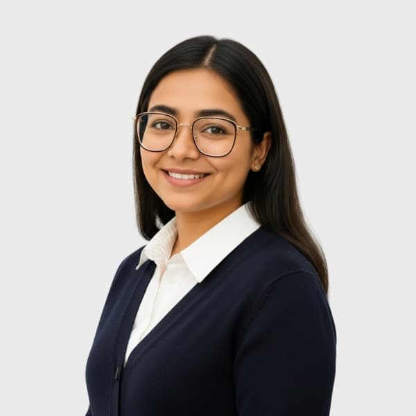 A woman with long dark hair and glasses smiles at the camera. She is wearing a white collared shirt under a navy cardigan, embodying the professional spirit of an IT staffing agency in Toronto, against a plain light gray background.