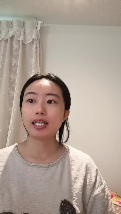 A young woman with long dark hair tied back is speaking, wearing a light-colored shirt, in a room with white walls and lace curtains—perhaps discussing IT and Finance jobs in Toronto.