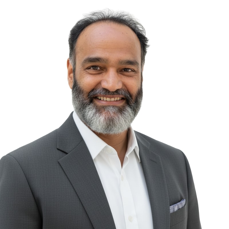 A man with a short gray beard and mustache smiles while wearing a dark suit jacket, white dress shirt, and pocket square—exuding confidence like a professional at a leading IT staffing agency in Toronto—standing against a white background.