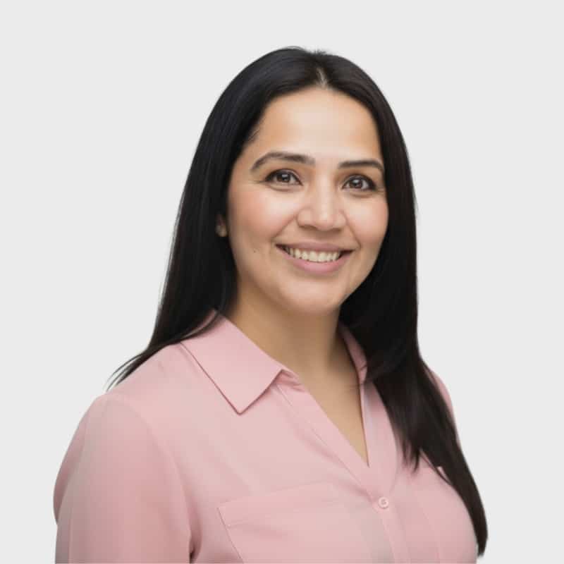 A woman with long dark hair, wearing a light pink button-up blouse, smiles at the camera against a plain white background, representing an IT staffing agency in Toronto.